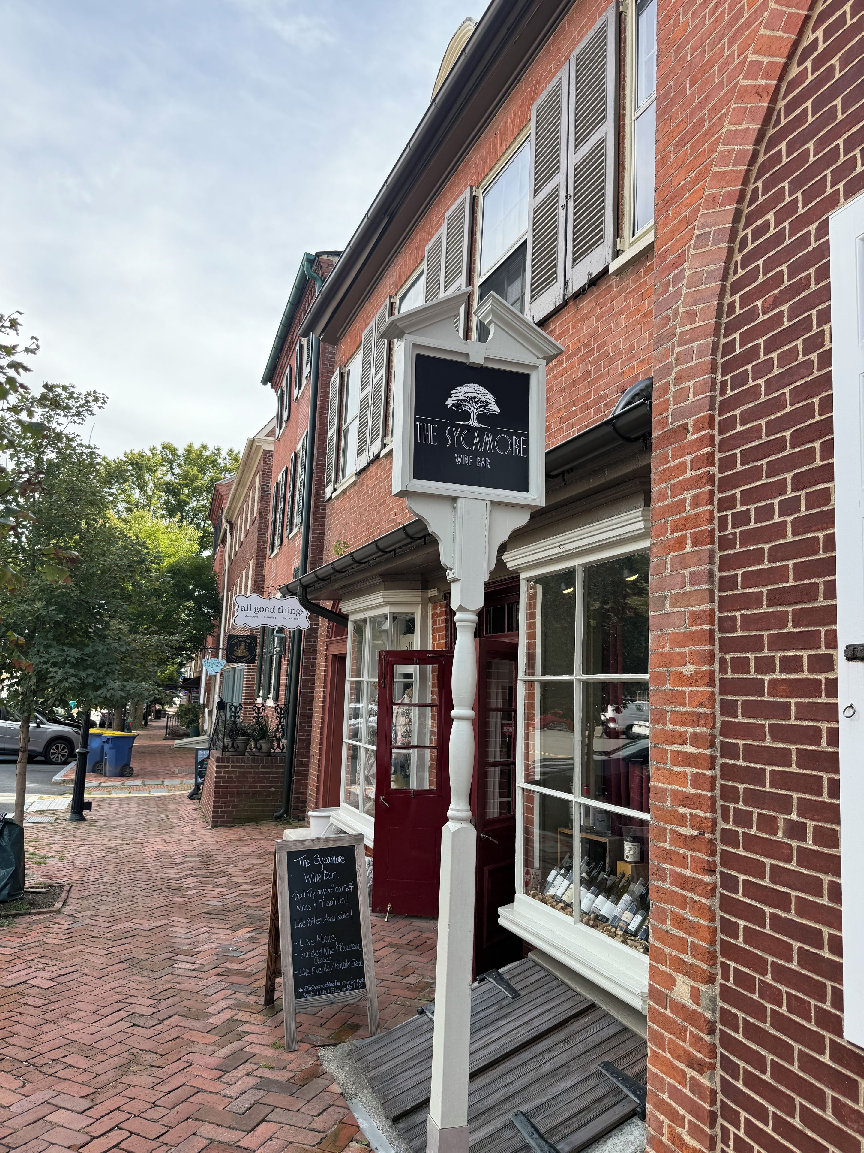 A brick building with a wine bar sign, a red door, and a window display of wine bottles.