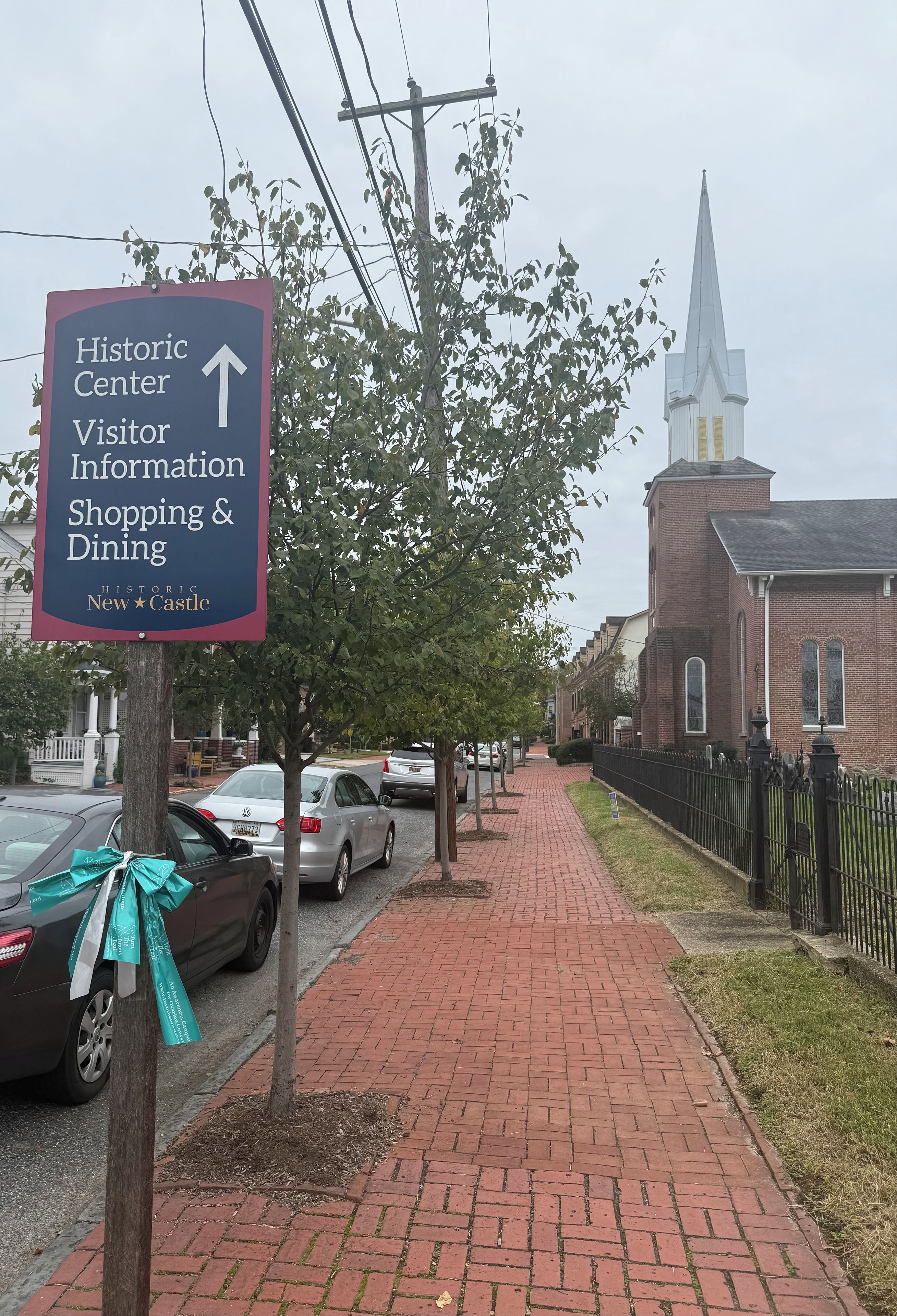 A brick pathway leading to a historic building with a steeple.