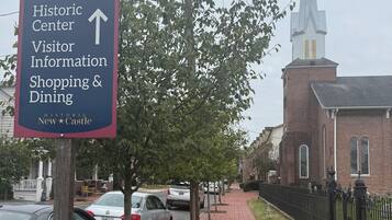 A brick pathway leading to a historic building with a steeple.