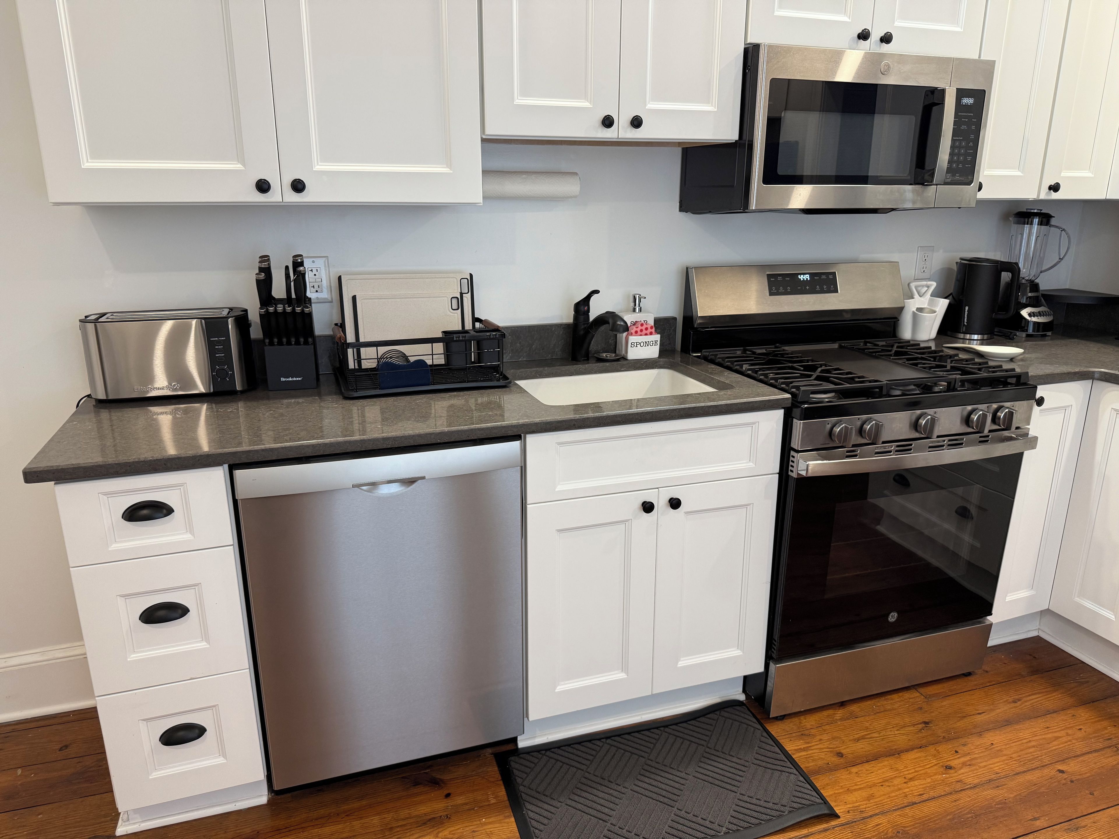 Una cocina moderna con armarios blancos, electrodomésticos de acero inoxidable y lavavajillas.