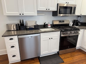 Una cocina moderna con armarios blancos, electrodomésticos de acero inoxidable y lavavajillas.