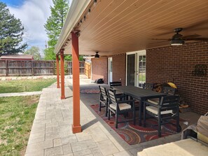 An outdoor patio with a brick wall, a covered seating area, and a table with chairs. - Charming 3-bedroom house with AC in amazing Denver neighborhood (Denver)