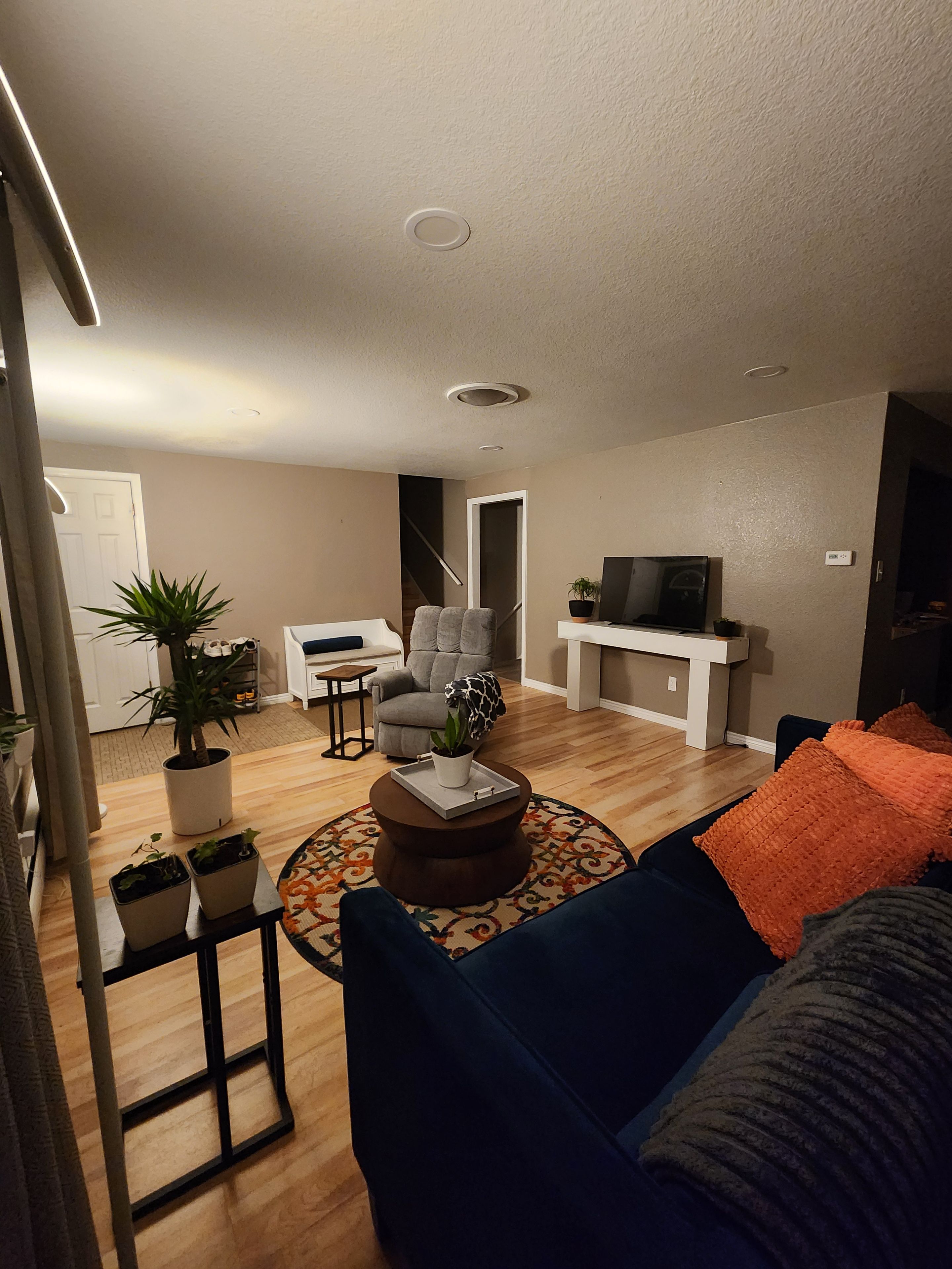 A living room with a sofa, a coffee table, and a television. There is a staircase leading to another room.