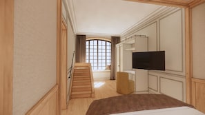 Habitación de hotel con cama, televisor, zona de estar y ventana con cortinas.