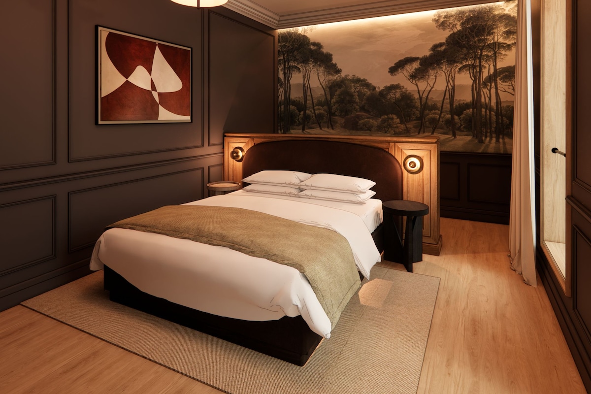 Un dormitorio con una cama grande, un cuadro, una lámpara de pared y un mural decorativo.