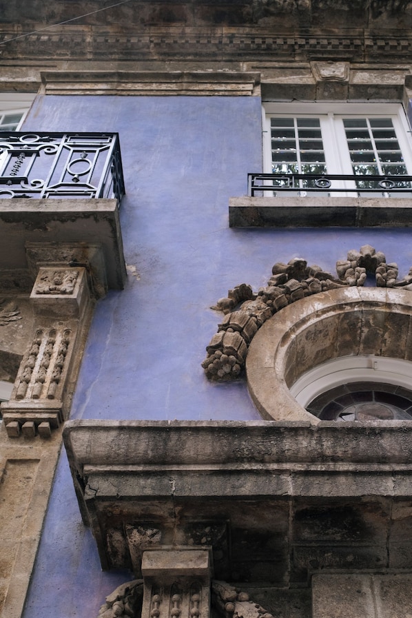 Un edificio con techo de tejas azules, balaustradas de piedra y una ventana circular.