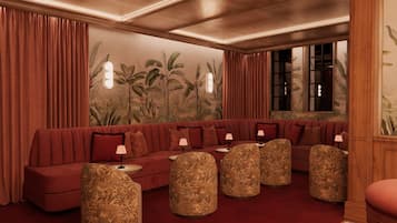 A room with a red sofa, patterned ottomans, and a wall with a tropical mural.