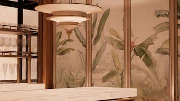 Zona de bar con techo de madera, lámpara colgante, encimera de mármol y taburetes rojos.