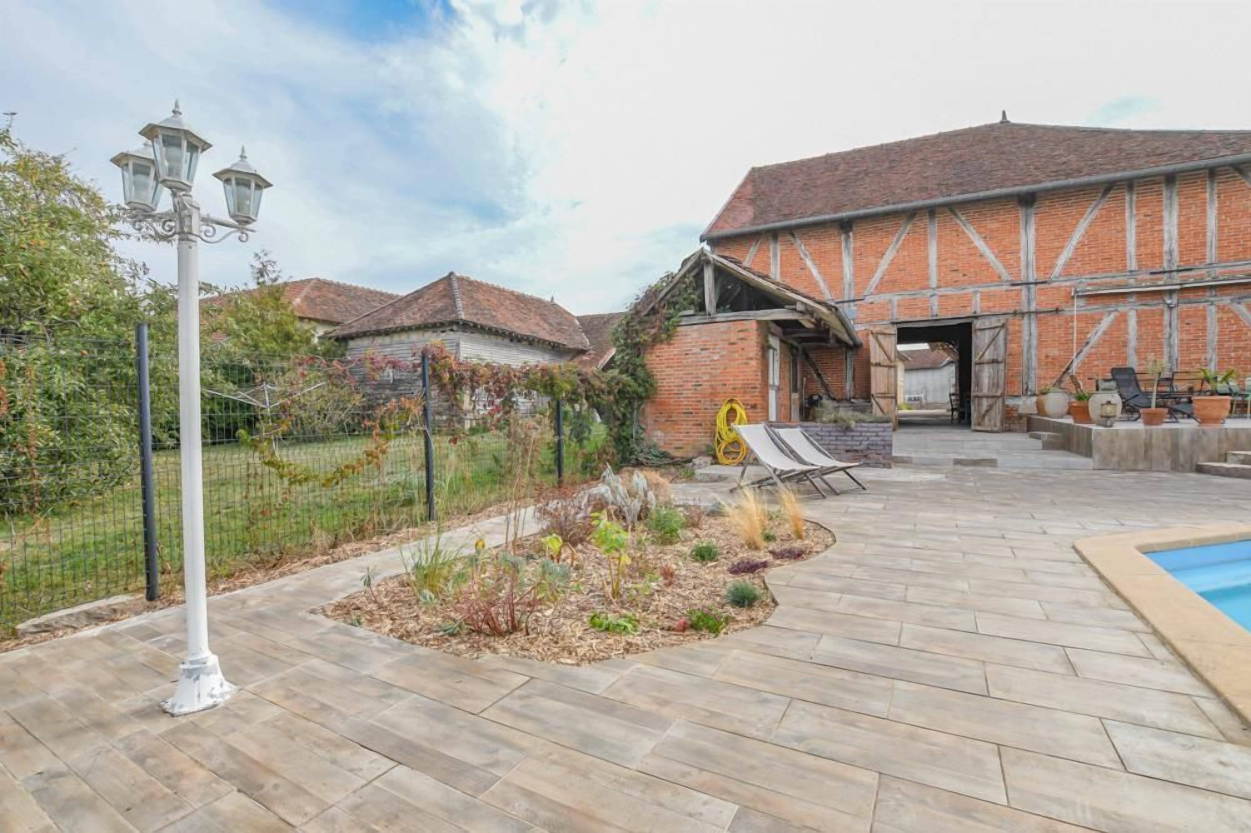 A courtyard with a pool, a brick building with a sloped roof, and a metal fence.