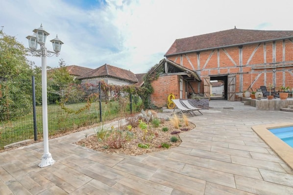 A courtyard with a pool, a brick building with a sloped roof, and a metal fence.