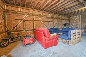 Une pièce avec des murs en briques apparentes, un canapé rouge, un divan bleu et une moto.