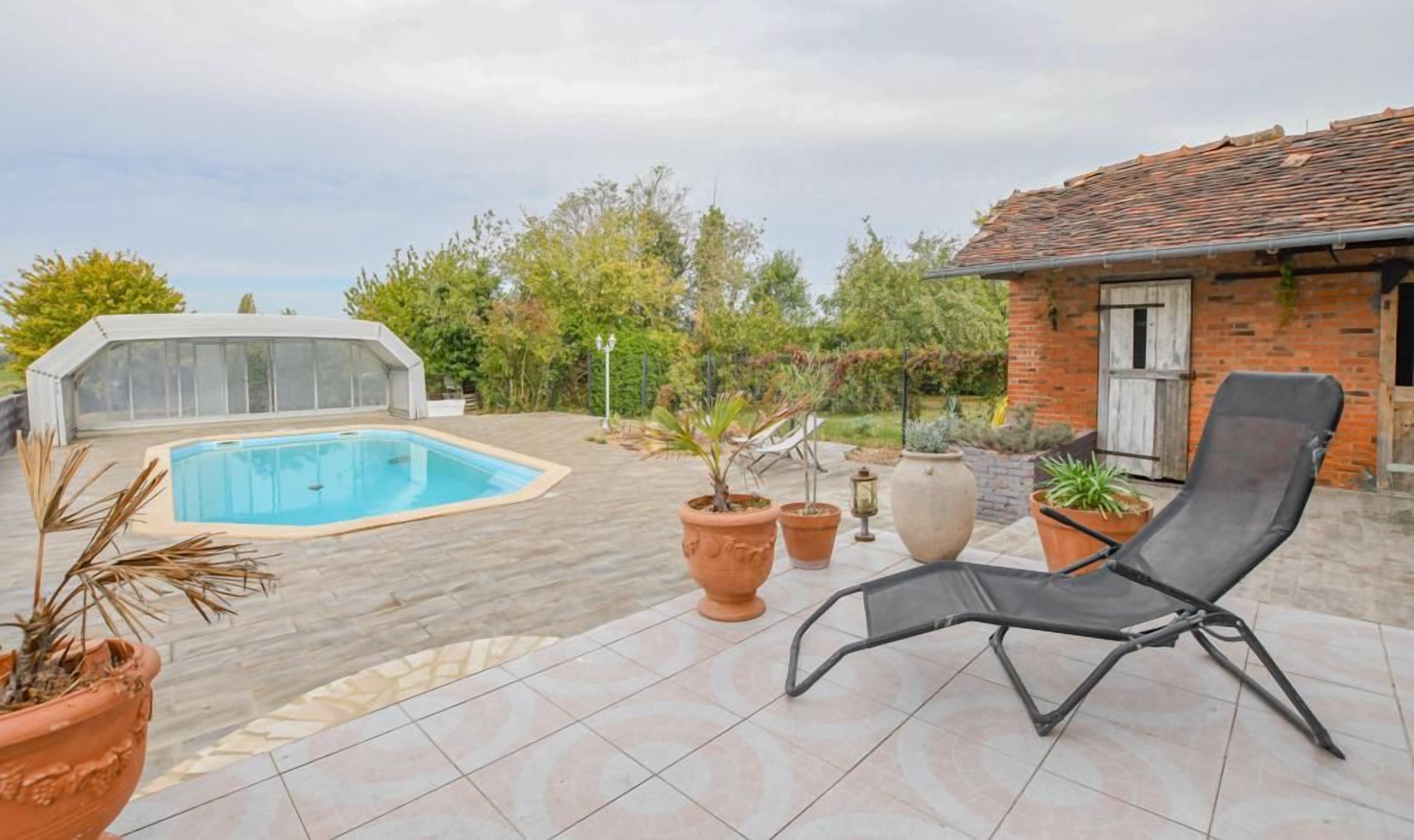 A swimming pool with a covered area, potted plants, and a lounge chair.
