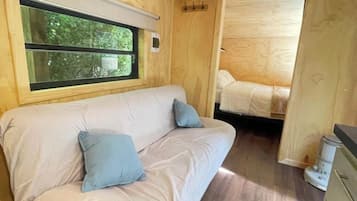 Un interior acogedor con sofá, cama, paredes de madera y ventana.