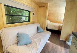 Un interior acogedor con sofá, cama, paredes de madera y ventana.