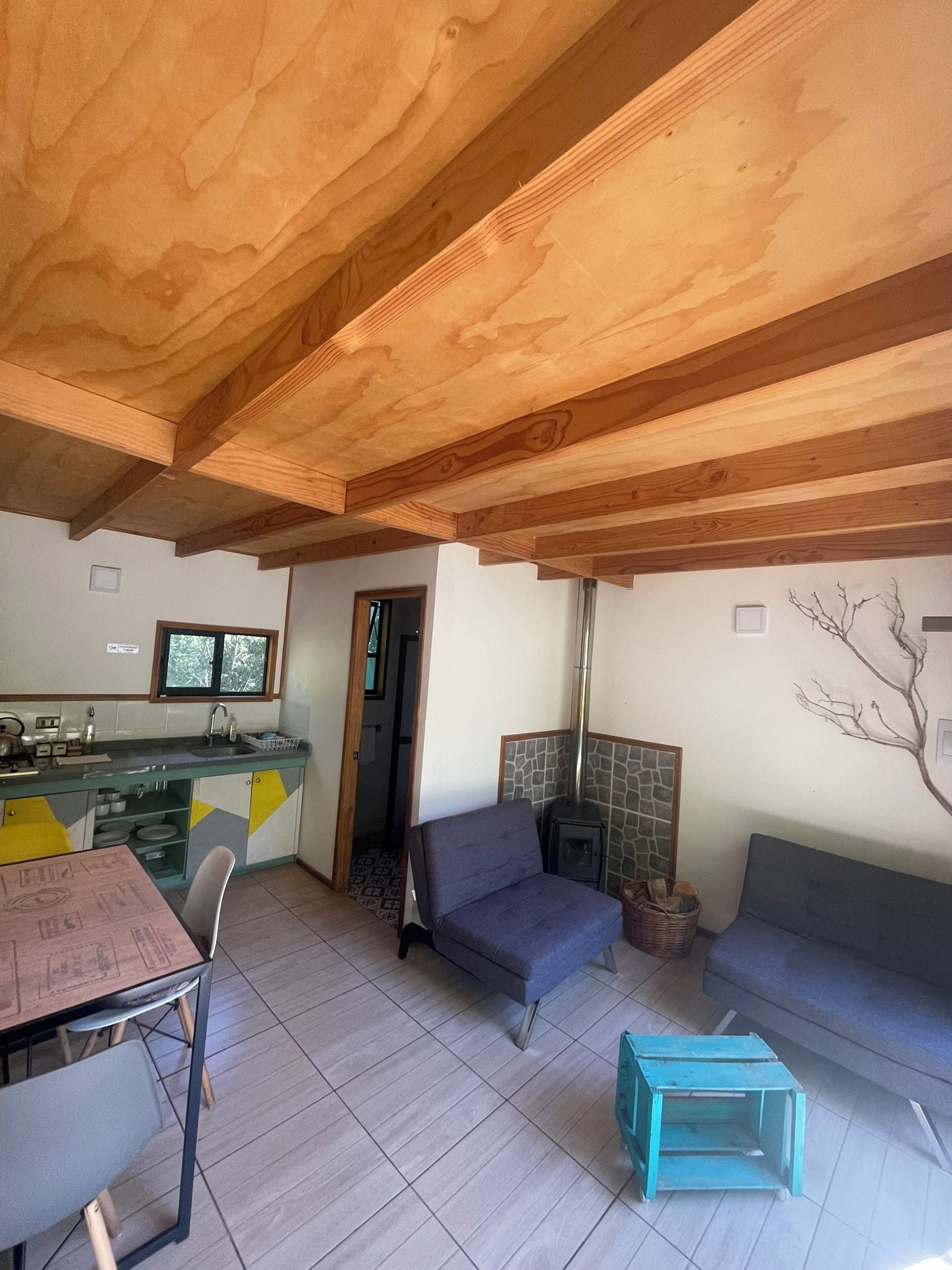 Uma sala de estar acolhedora com lareira, um espaço de jantar com mesa e cadeiras, e uma cozinha com janela.