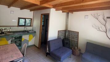 Uma sala de estar acolhedora com lareira, um espaço de jantar com mesa e cadeiras, e uma cozinha com janela.