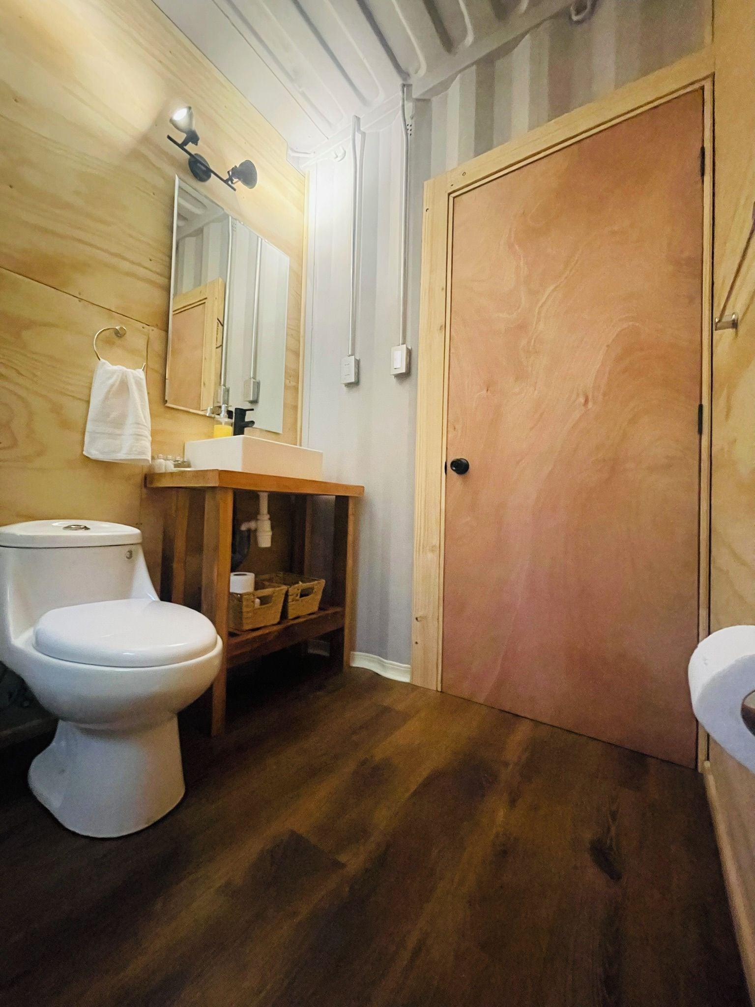 Un baño con tocador de madera, dos inodoros y un espejo.