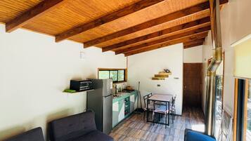 Uma sala de estar ampla com teto de madeira, uma mesa de jantar com cadeiras e uma cozinha equipada.