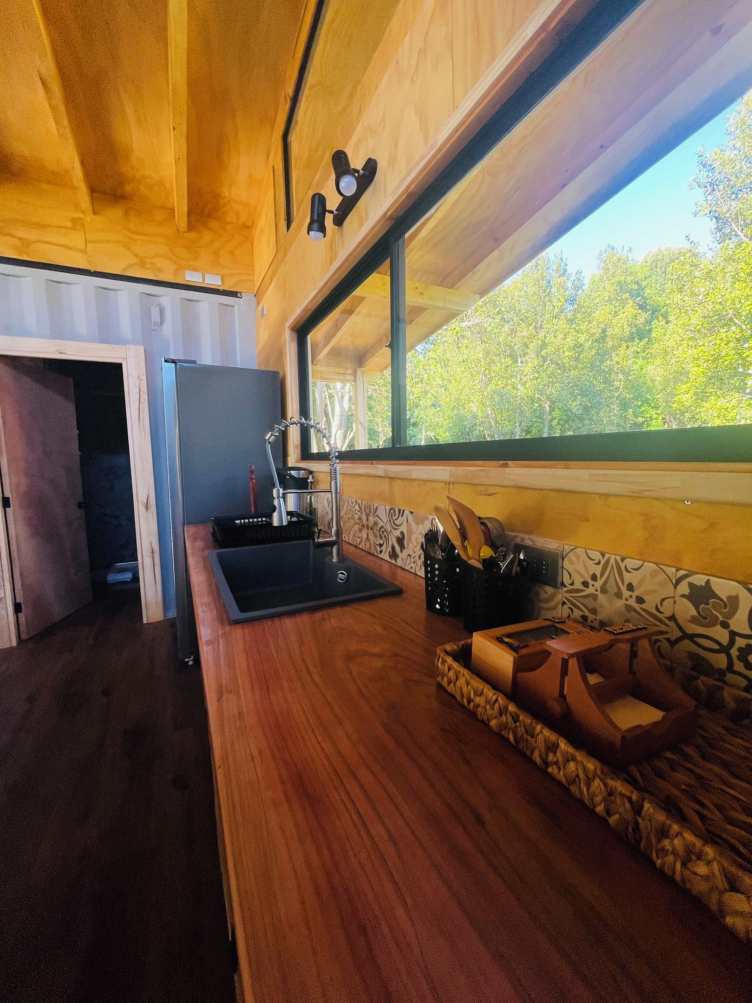 Una cocina con mostrador de madera, un lavamanos y una ventana con vistas a zonas verdes.