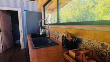 Una cocina con mostrador de madera, un lavamanos y una ventana con vistas a zonas verdes.