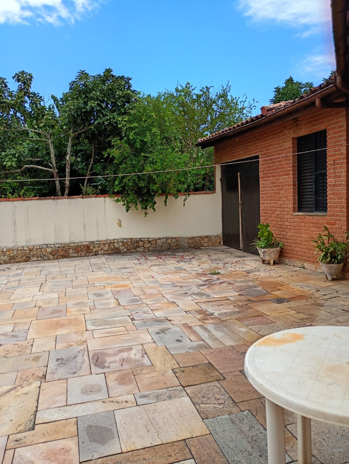 A patio area with stone flooring, a brick building, and a wall with climbing plants.
