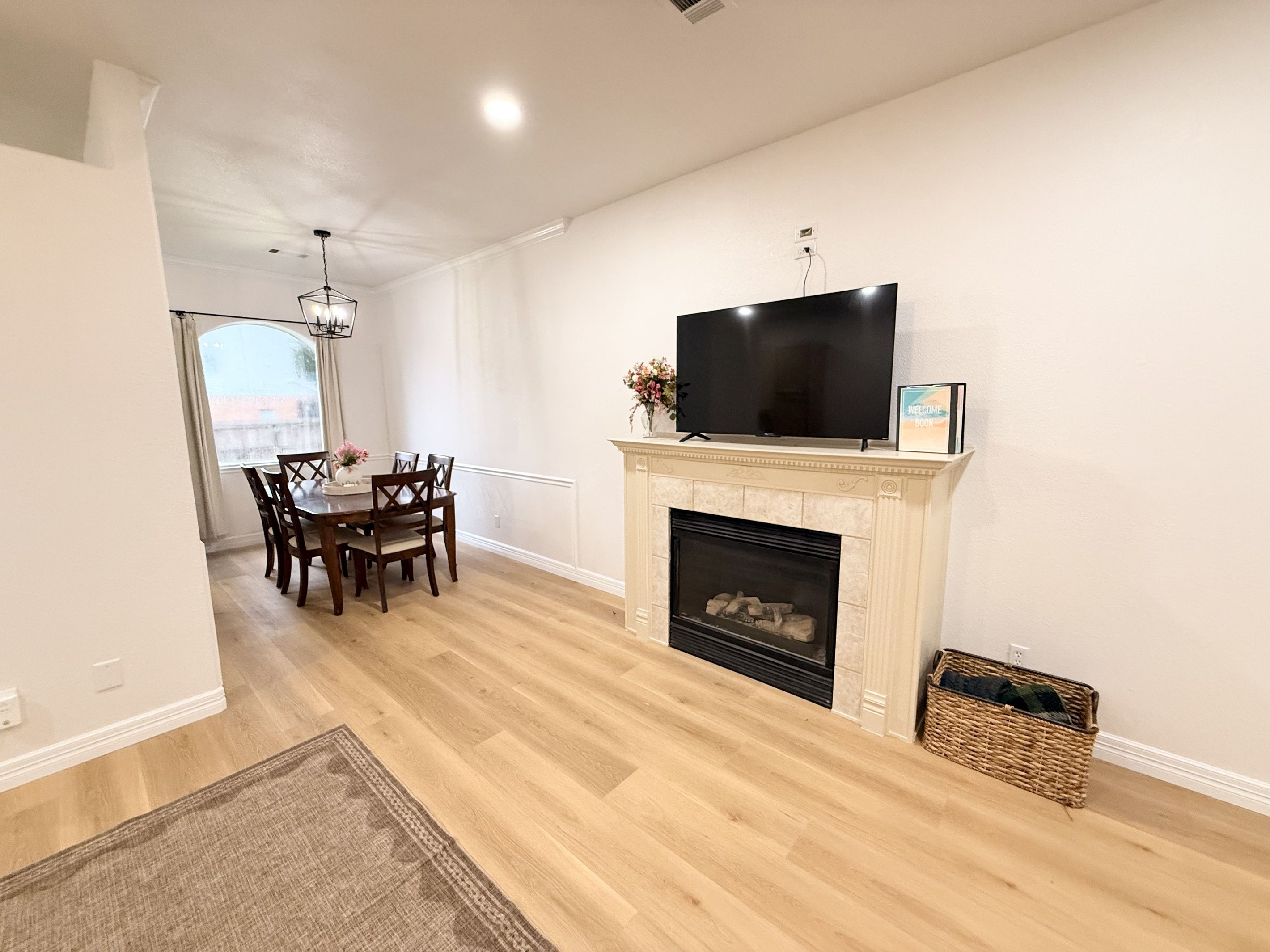 Una sala de estar moderna con chimenea, un televisor de pantalla plana montado encima y una zona de comedor con mesa y sillas.