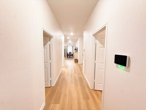 A hallway with wooden flooring and white walls, leading to a dining area with a table and chairs. - 3 bedroom 2 bath home in Lumberton (Lumberton)