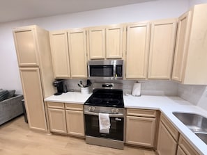 A kitchen with beige cabinets, a stainless steel microwave, a stove, and a sink. - 3 bedroom 2 bath home in Lumberton (Lumberton)