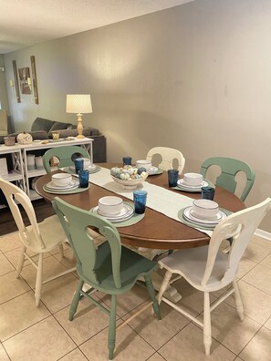 A dining area with a round table set for four, surrounded by green chairs, with a lamp and decorative items on the table. - Spacious 3-bedroom house in superb Abilene with AC (Abilene)