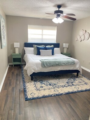 A bedroom with a bed, nightstands, a ceiling fan, a window with blinds, and a patterned rug. - Spacious 3-bedroom house in superb Abilene with AC (Abilene)