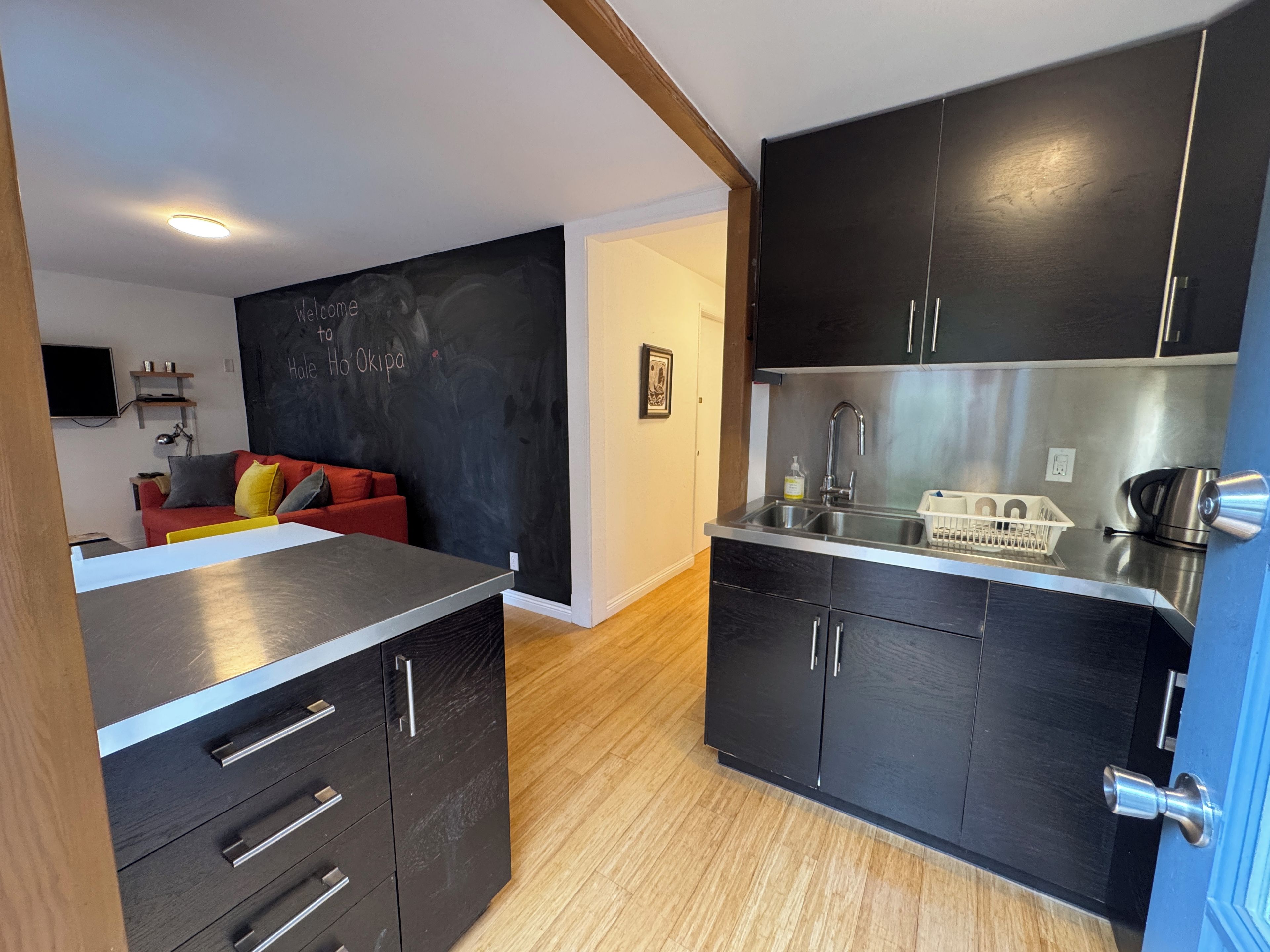 A compact kitchen with dark cabinets, a stainless steel sink, and a small countertop.