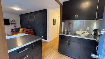 A compact kitchen with dark cabinets, a stainless steel sink, and a small countertop.
