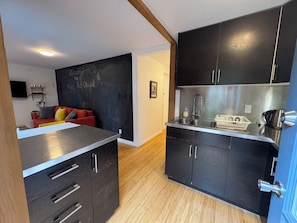 A compact kitchen with dark cabinets, a stainless steel sink, and a small countertop. - Cozy Tuck-Under Studio in Silver Lake w/ Private Tropical Yard, Orange Trees (Los Angeles)