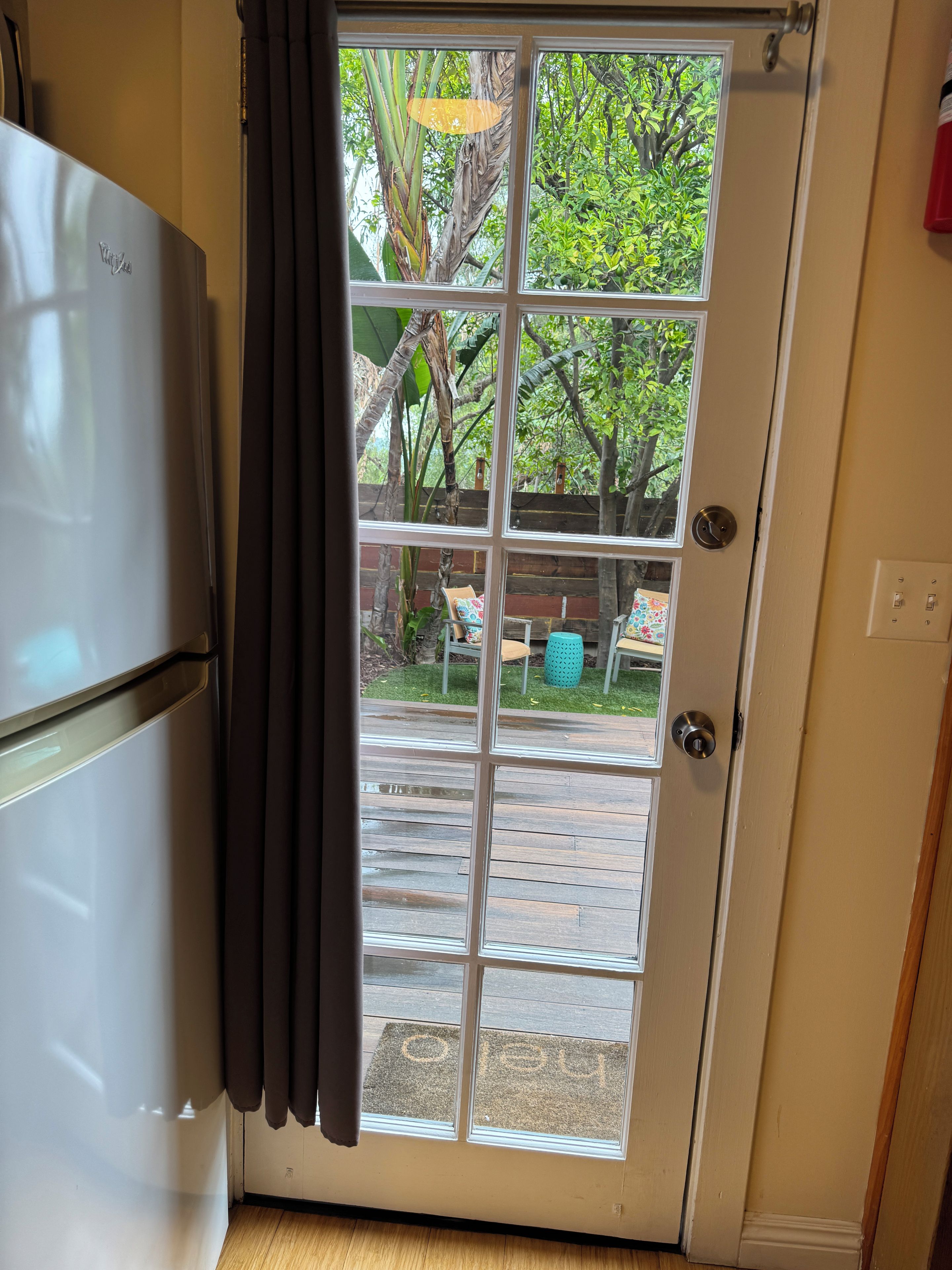 A kitchen with a refrigerator and a sliding glass door leading to an outdoor patio area.