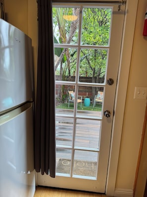 A kitchen with a refrigerator and a sliding glass door leading to an outdoor patio area. - Cozy Tuck-Under Studio in Silver Lake w/ Private Tropical Yard, Orange Trees (Los Angeles)