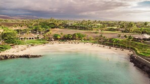 A coastal resort with a sandy beach, palm trees, and a view of distant mountains. - Luxury Villa Designer updates HI Gem Kings (Waimea)
