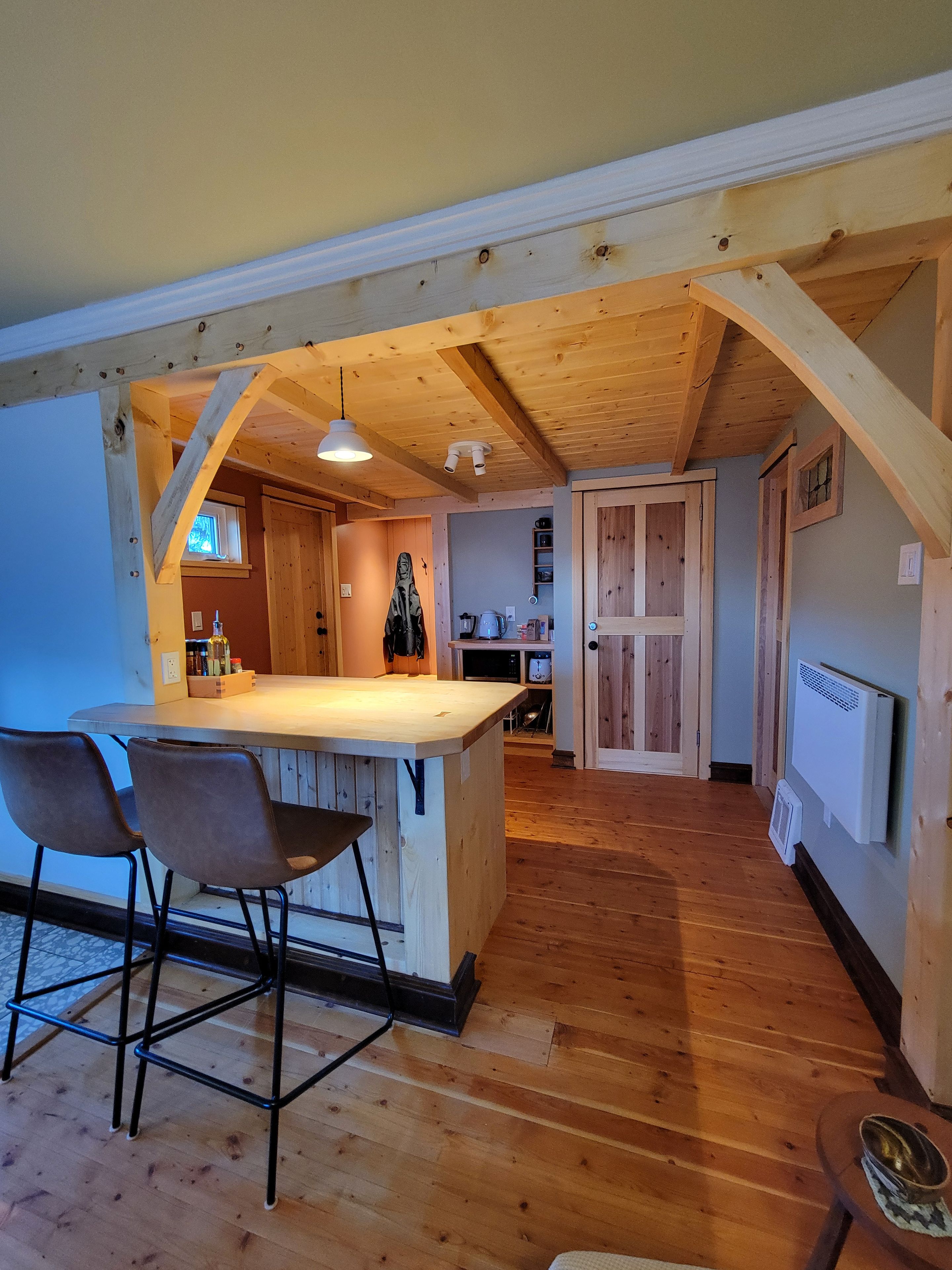 A kitchen with wooden beams, a bar area with stools, and a view into the dining room.
