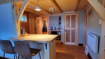 A kitchen with wooden beams, a bar area with stools, and a view into the dining room.