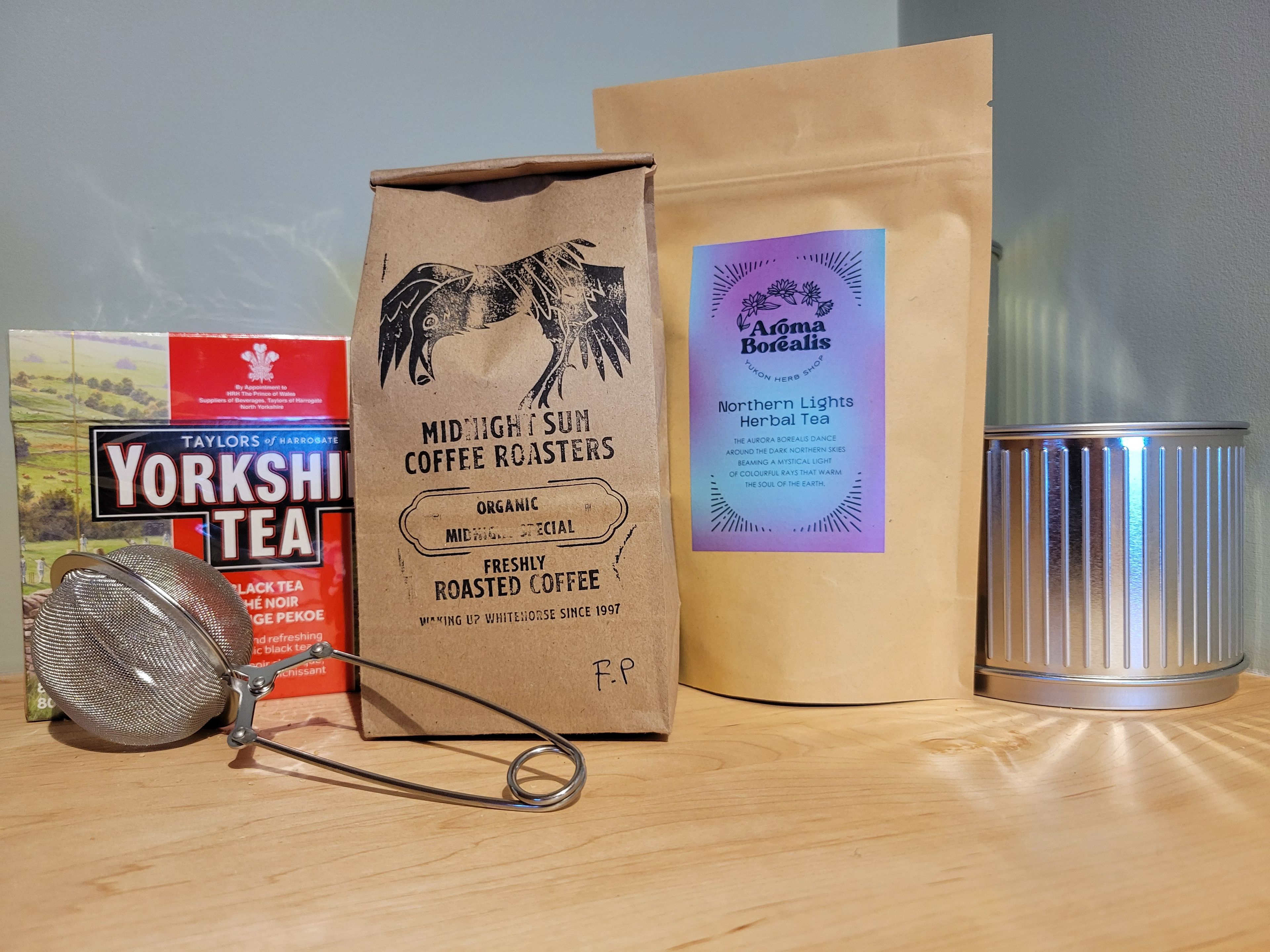 A coffee roaster, a Yorkshire Tea bag, a bag of Midnight Sun Coffee Roasters, and a canister.