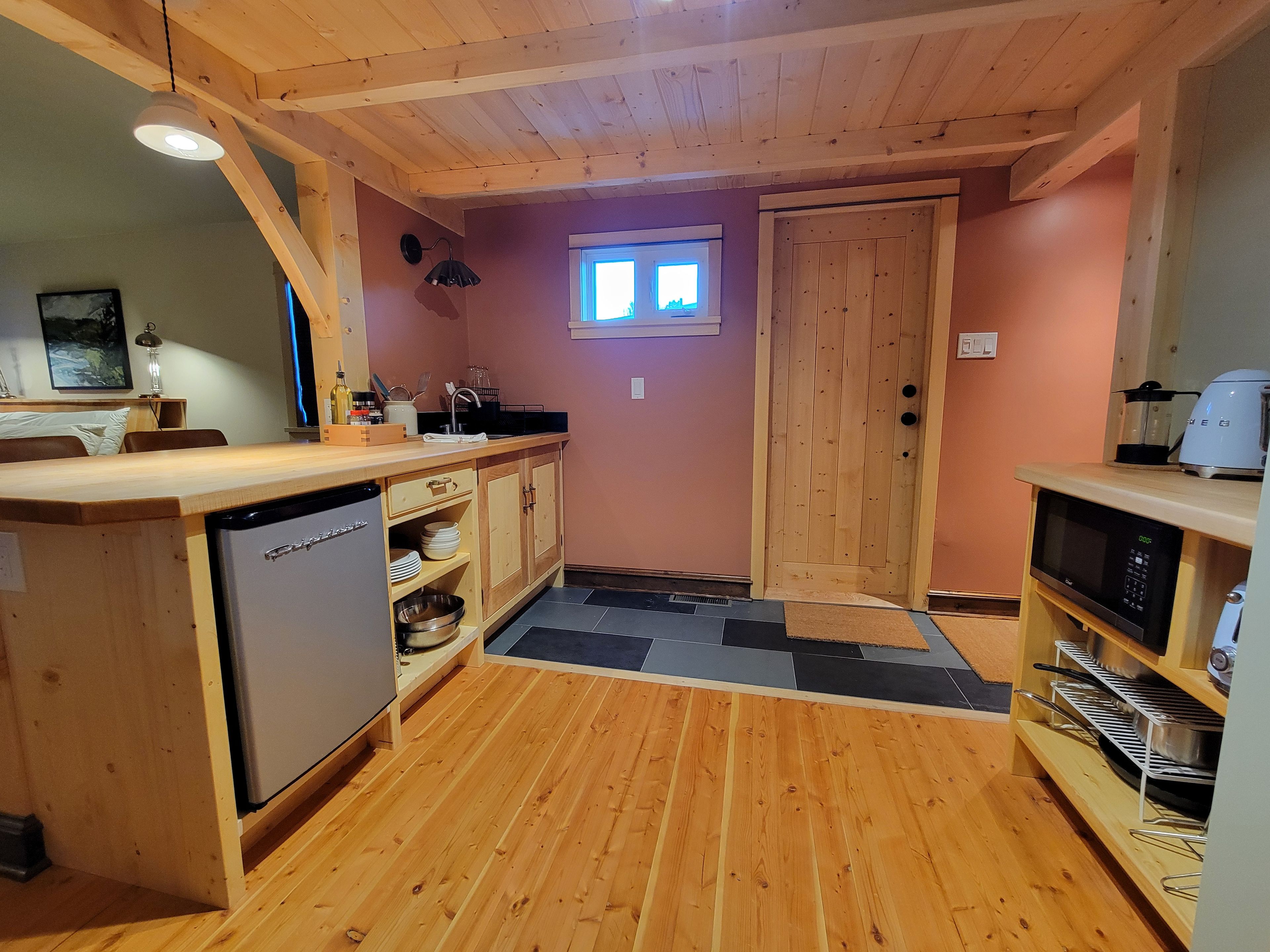 A compact kitchen with wooden cabinets, a dishwasher, a microwave, and a sink.