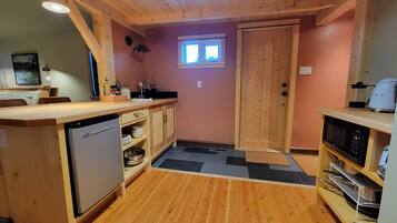 A compact kitchen with wooden cabinets, a dishwasher, a microwave, and a sink.