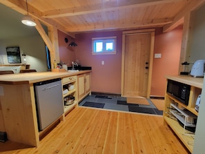 Een kleine keuken met houten kastjes, een vaatwasser, een magnetron en een spoelbak.