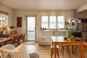 A modern kitchen with white cabinetry, a built-in oven, and a stainless steel refrigerator. - Little Eden by Waiheke Pure (Waiheke Island)
