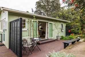 A small house with a deck, a table, and chairs. - Little Eden by Waiheke Pure (Waiheke Island)
