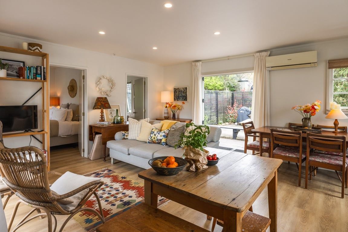 A living room with a sofa, dining table, and chairs, a television, and a bookshelf.