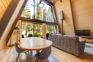 A modern interior with a dining area, sofa, and TV. - 1 Woodland Walk to the SR Village with hot tub, fireplace & patio (Sunriver)