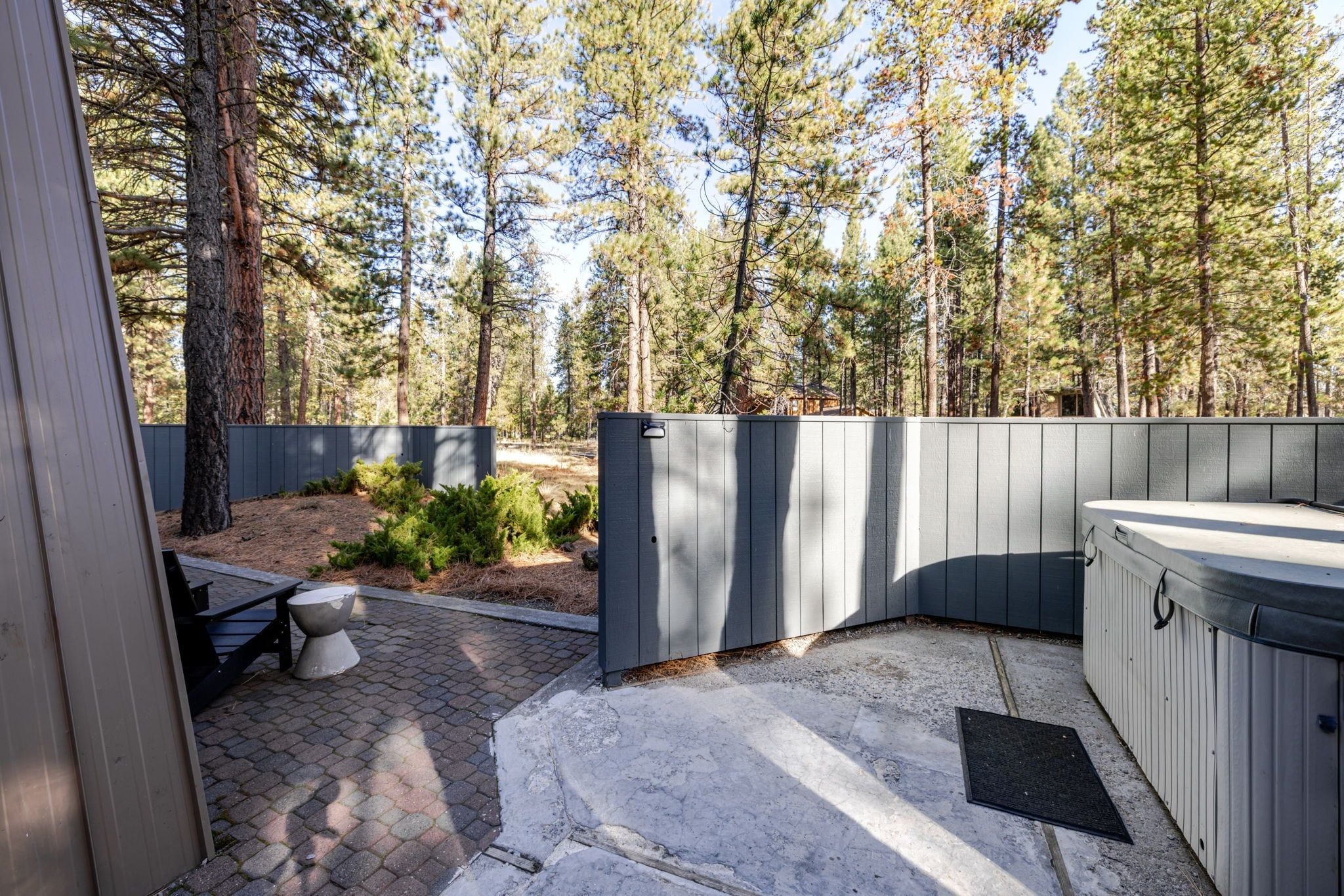Un espacio al aire libre techado con un jacuzzi, un banco y una mesita.