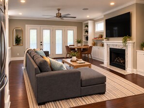 A living room with a sectional sofa, dining table, chairs, a fireplace, and a television.