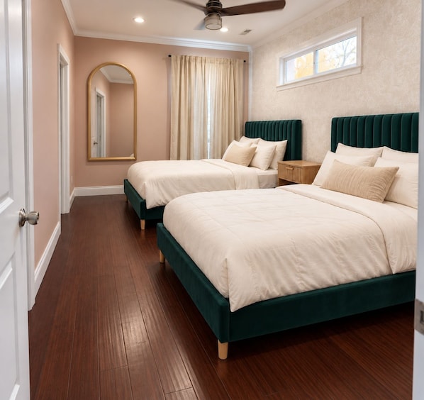 A bedroom with two beds, a ceiling fan, and a window with curtains.
