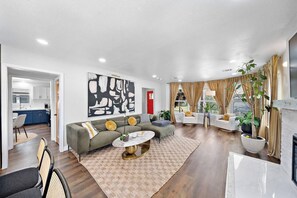 Ein modernes Wohnzimmer mit einer Couch, einem Couchtisch und einem Essbereich mit Stühlen.
